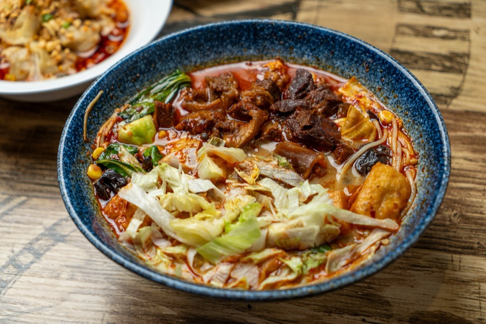 Spicy noodle soup with braised beef and cabbage in a blue bowl