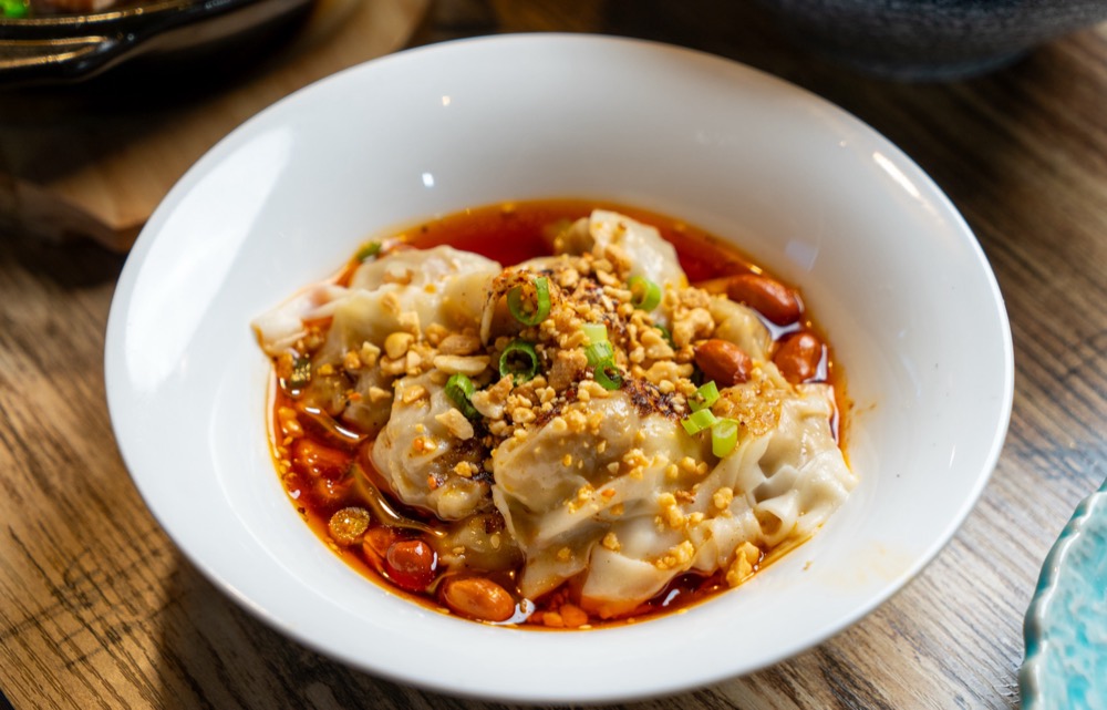 Wontons in chili oil topped with peanuts and scallions