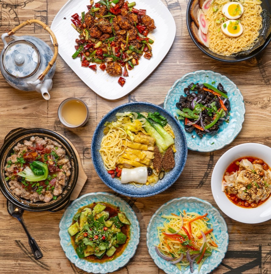 A table spread of Ji Bei Chuan noodle soups, ramen, spicy chicken, wontons and tea